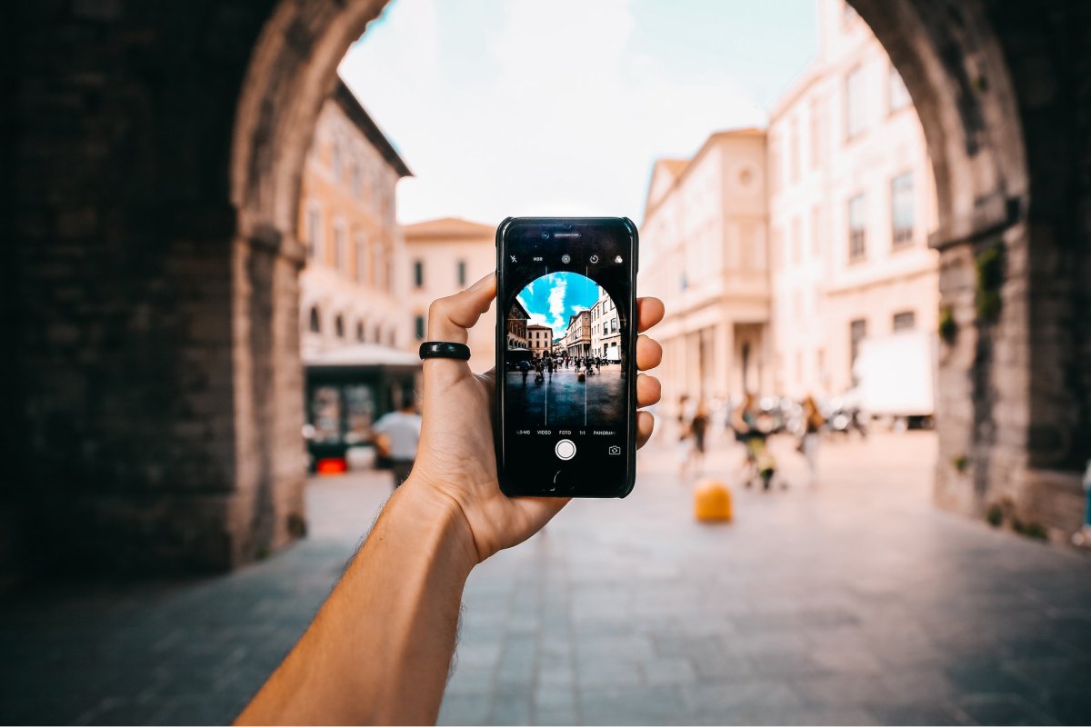 A person holding up a smartphone to take a photo of a plaza. 