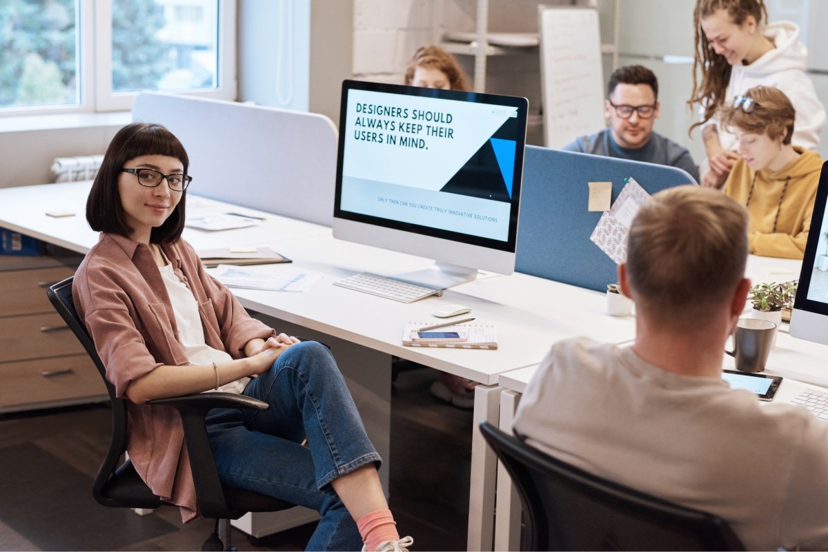 A design team sitting together with a design quote on a woman’s computer monitor.