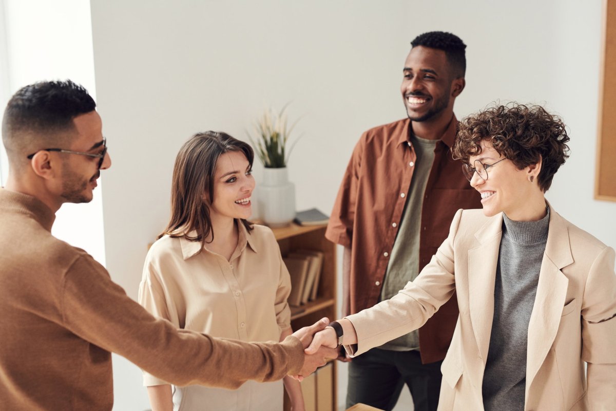 Two people shaking hands while two others standby. 