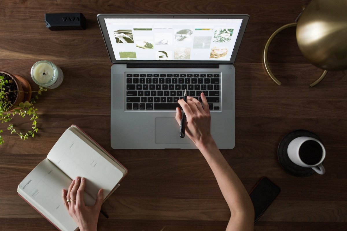 A person holding their place in a notebook and clicking a button on their computer. 