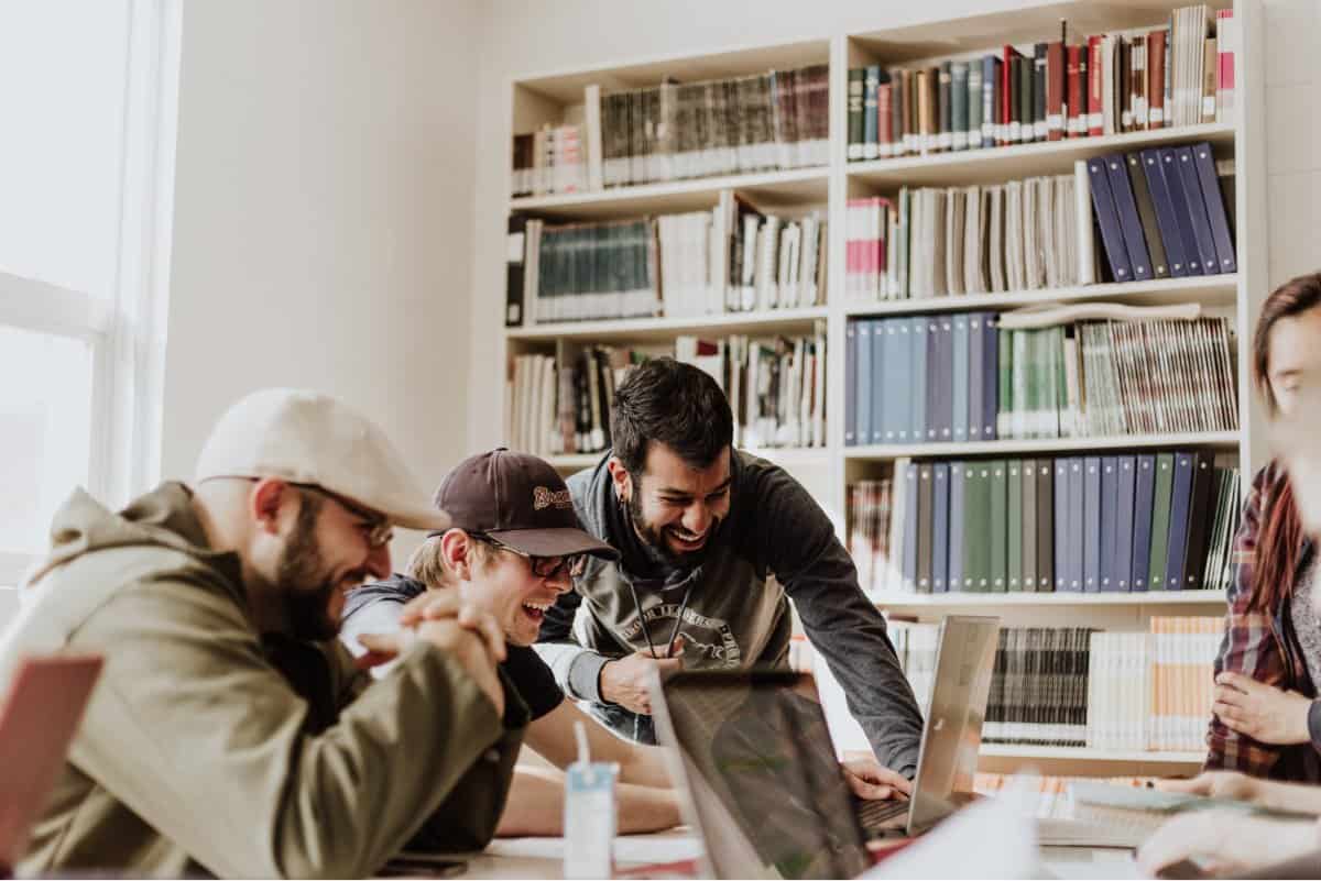 A photo of a mobile app design team laughing and commiserating about something on a laptop screen.