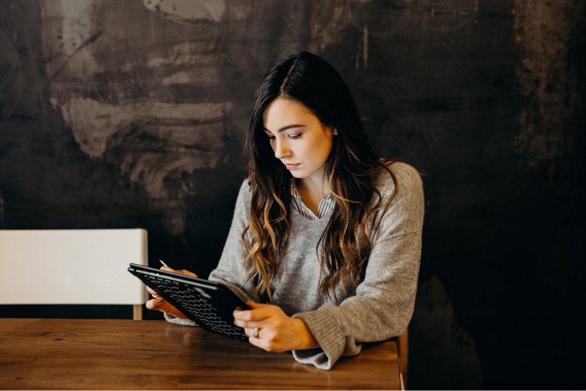 A photo of a woman using a tablet with a stylus.