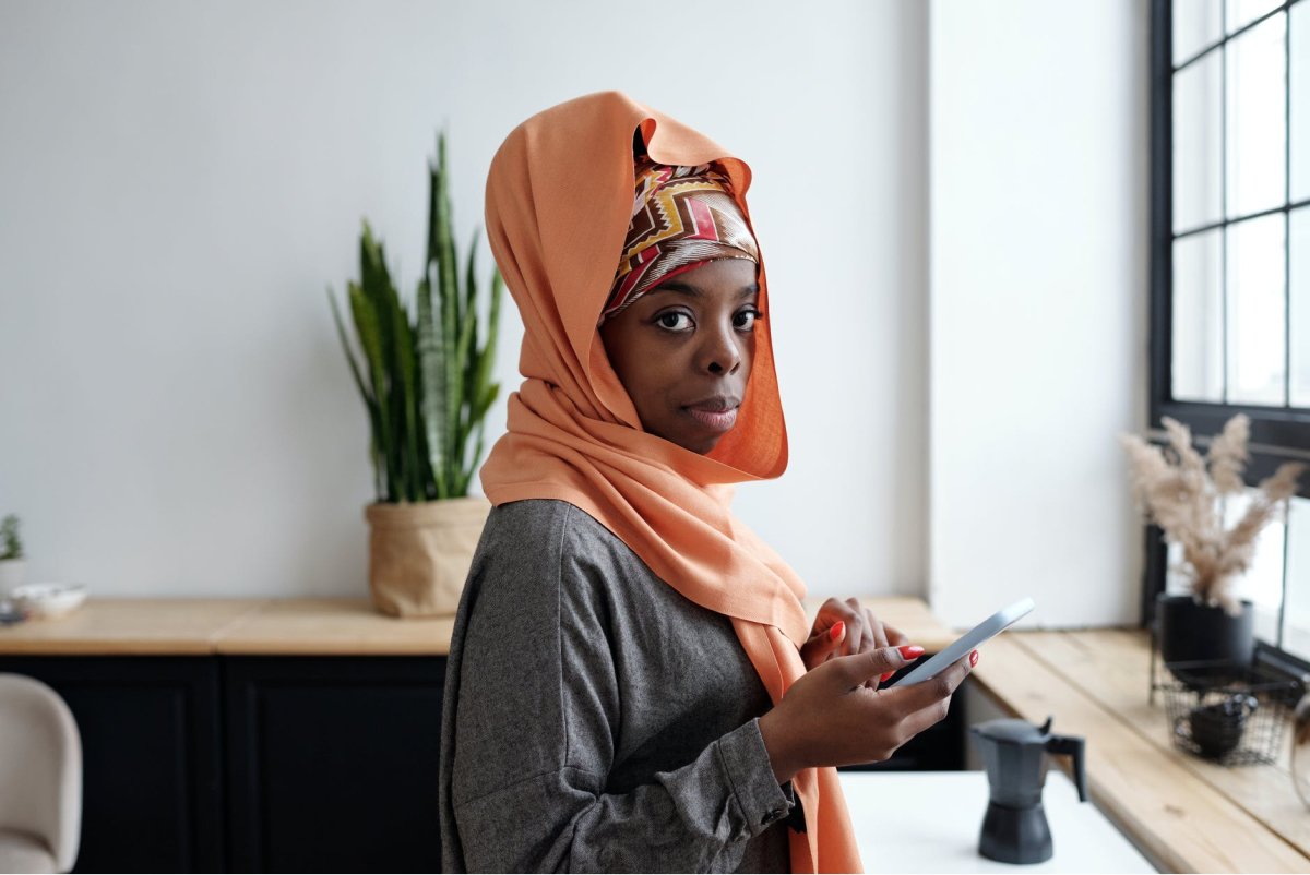 A woman in a colorful headscarf holding a smartphone. 