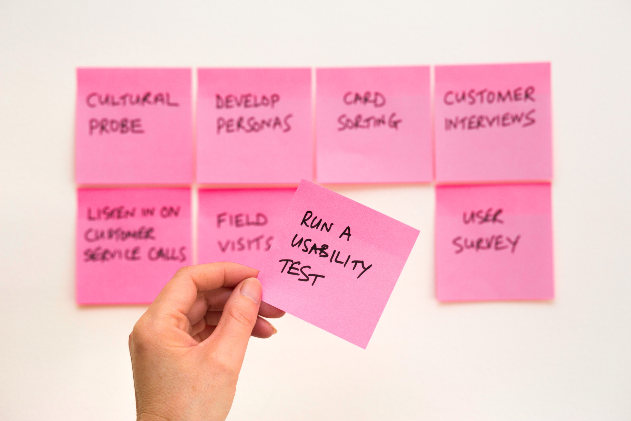 A bunch of pink Post-It notes, with one in focus saying “Usability Test”