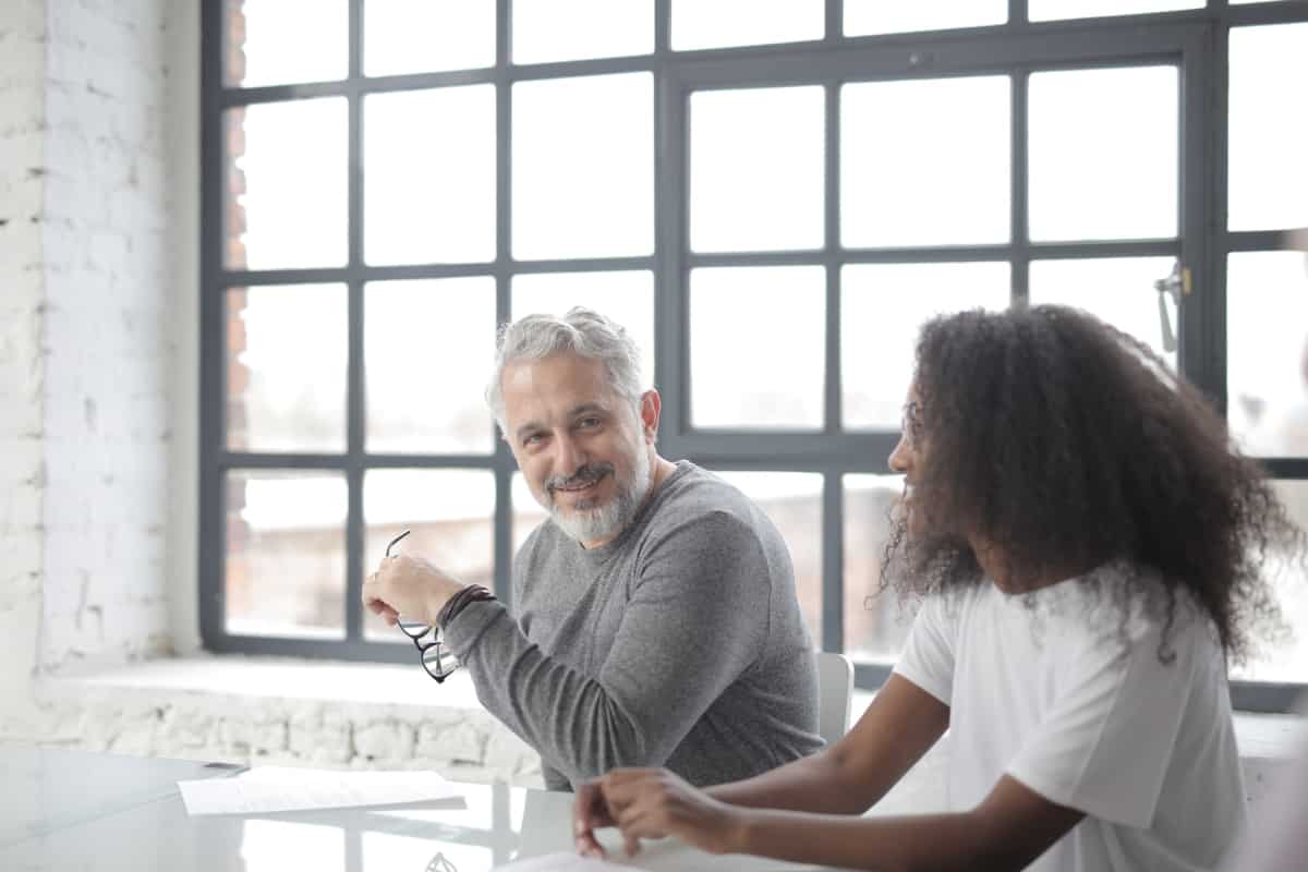 An older man and younger woman are paired up at work to learn from one another.