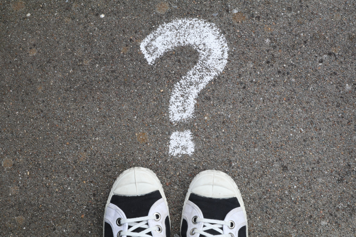 A question mark drawn on the ground with chalk and shoes. 