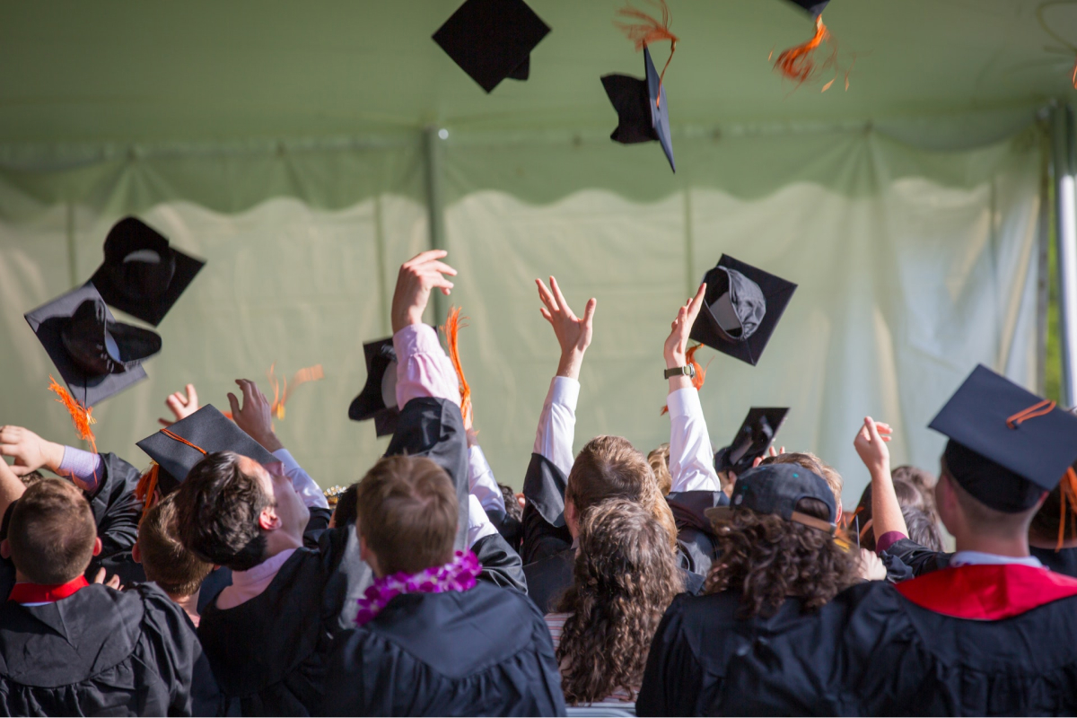 Students at their graduation, tossing their caps in the air. 